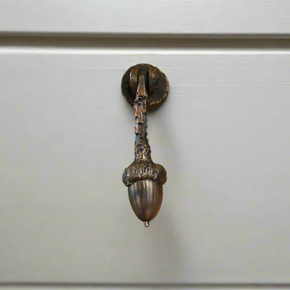 Bronze cabinet hanging hinged pull with one acorn on the end of a branch. Traditional patina