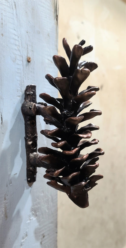 White pine cone bronze door knocker mounted to door